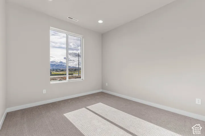 Wall-to-wall carpeted room with recessed lighting and a large window