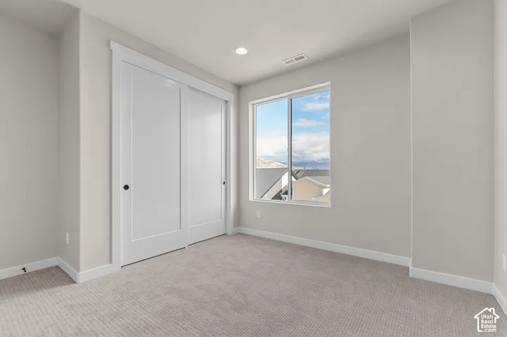Plush carpet flooring, recessed ceiling lighting, and a window with mountain scenery