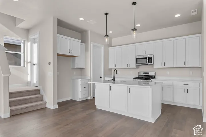 Kitchen featuring white cabinetry with dark hardware, a center island, stainless steel appliances, and recessed lighting