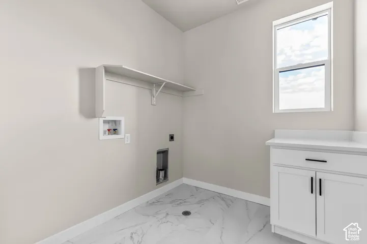 White shaker-style cabinetry with matte black hardware, white countertop, window with white trim, wall-mounted shelving unit, and marble-look flooring