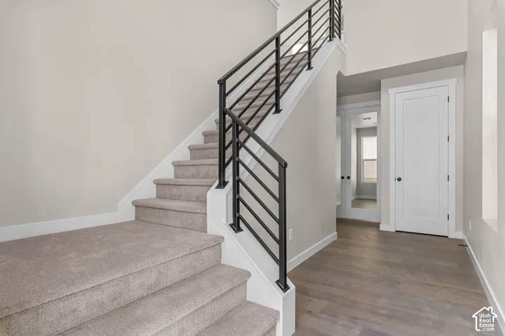 Carpeted staircase with black metal railings, leading to a lofted space