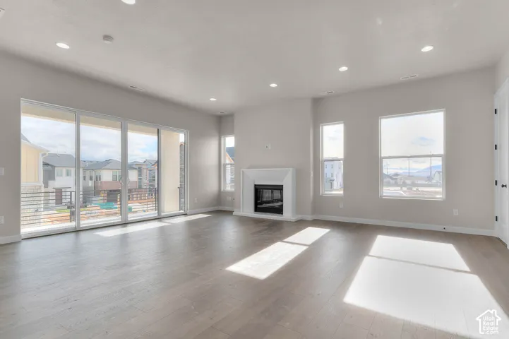 Wood-finish flooring, recessed lighting, and a white fireplace with a black insert