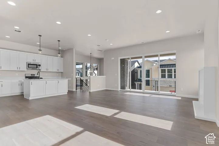 Open-concept living area with wood-finish flooring, white cabinetry, a kitchen island, and a built-in fireplace feature