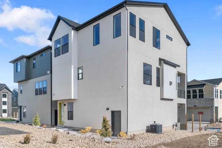 Contemporary exterior with contrasting siding panels, an attached balcony, and a vibrant yellow entry door