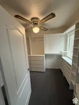 Walk-in closet with built-in shelving, integrated drawers, and a ceiling fan with light fixture