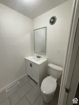 Contemporary vanity with integrated sink, rectangular mirror, and light gray tile flooring