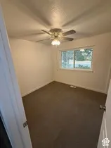 Ceiling fan with integrated lighting, carpeted flooring, and a single window with white trim