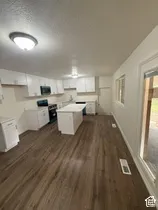 Bright kitchen featuring wood-finish flooring, white cabinetry, a central island, and modern overhead lighting
