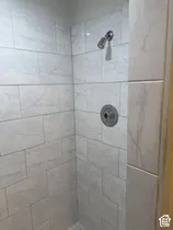 Shower with large format subway tile surround, chrome showerhead, and circular control valve