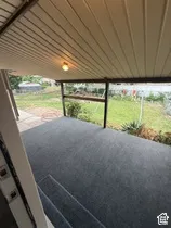 Covered porch with dark gray outdoor carpeting and integrated ceiling light
