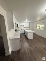 Kitchen featuring a center island, white cabinetry, white countertops, a single basin sink, and wood-finish flooring