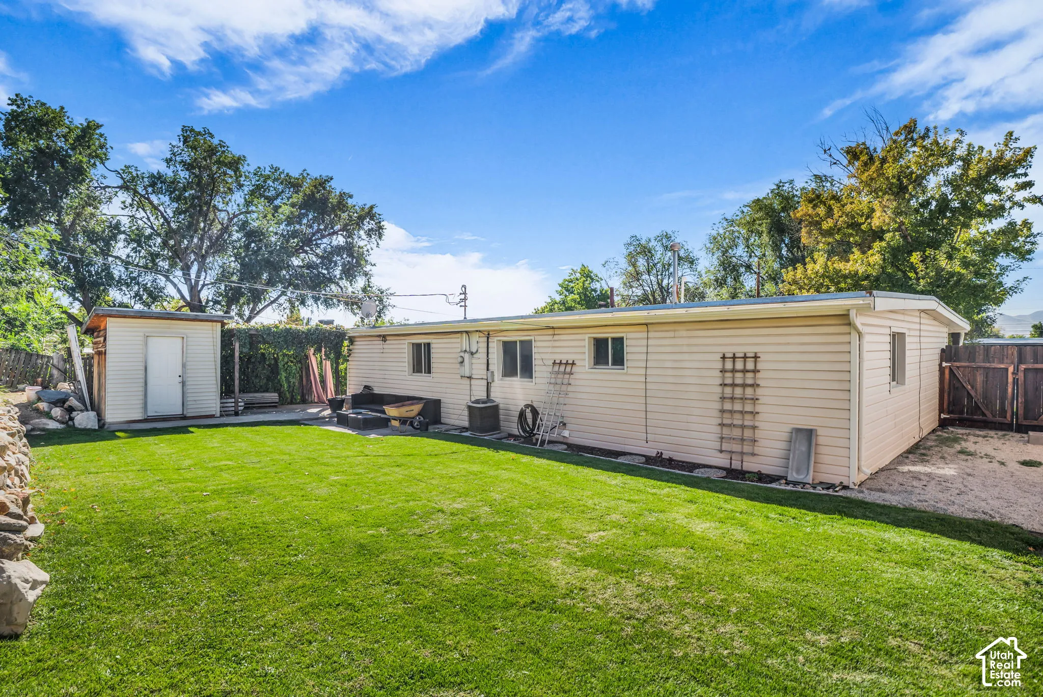 Expansive lawn with a detached storage shed, privacy fencing, and exterior wall-mounted trellises