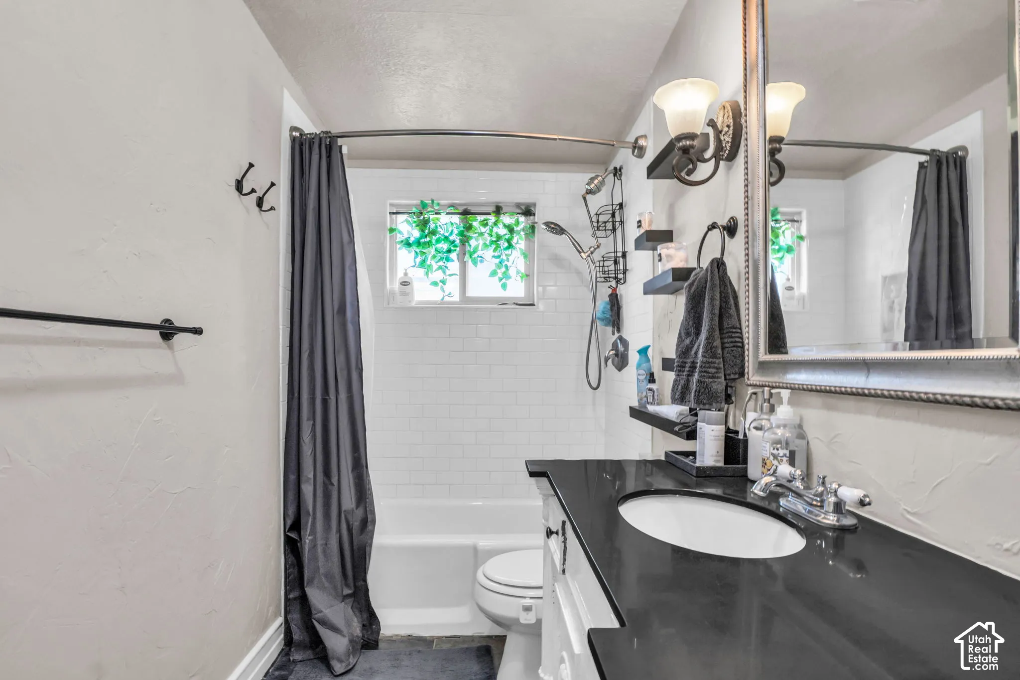 Bathroom featuring a black countertop vanity with an oval sink, white subway tile shower surround, and a fixed window