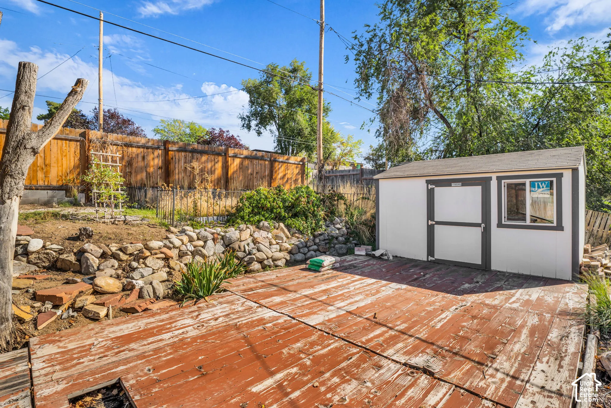 Storage shed with a window, wood fencing, and a retaining wall