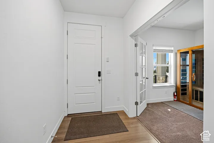 Entryway with wood-finish flooring, a white paneled door, and smart lock hardware