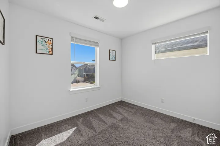 White walls, gray patterned carpeting, white trim, recessed lighting, and a single window with blinds