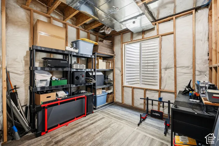 Unfinished space featuring wood framing, insulation, a single window, exposed ductwork, and wood-finish flooring