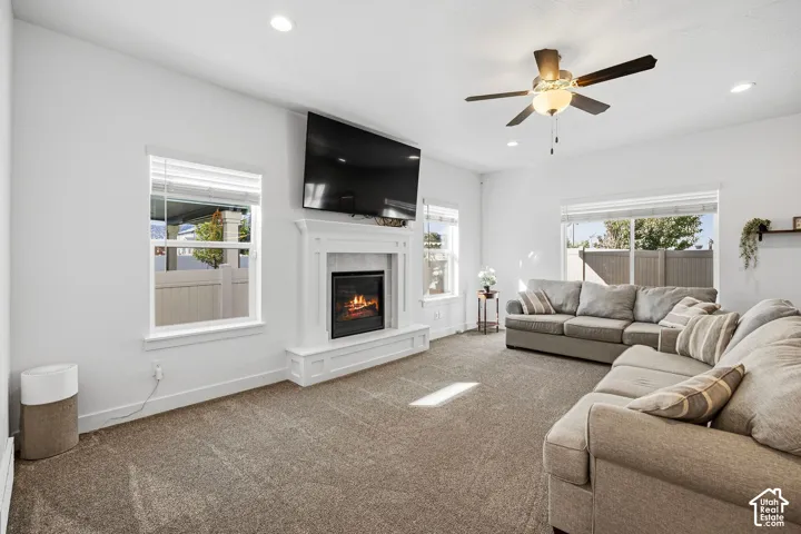 Living area featuring a white mantel fireplace, recessed lighting, ceiling fan, and multiple windows