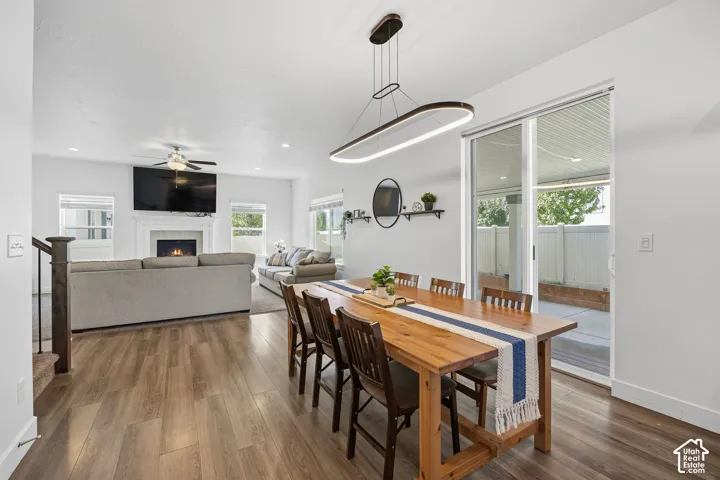 Open-concept living space with wood-finish flooring, a white-mantled fireplace, and a contemporary linear light fixture