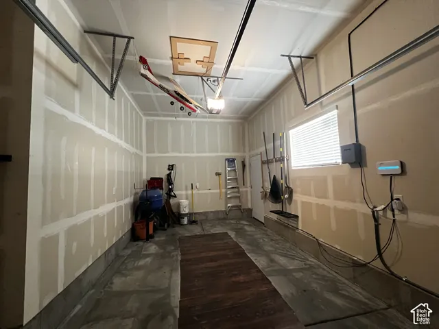 Attached garage featuring a concrete floor and a window with horizontal blinds