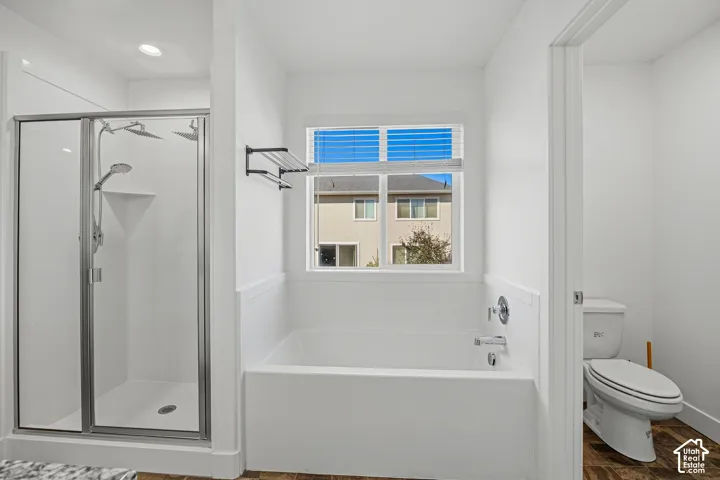 White soaking tub with chrome fixtures, glass-enclosed shower with dual showerheads, and recessed lighting