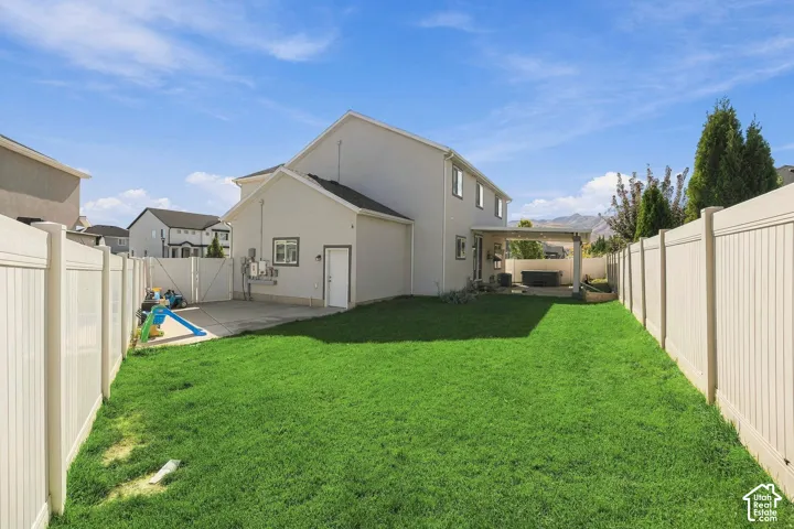 Expansive lawn area with perimeter fencing, a covered patio, and a concrete pad