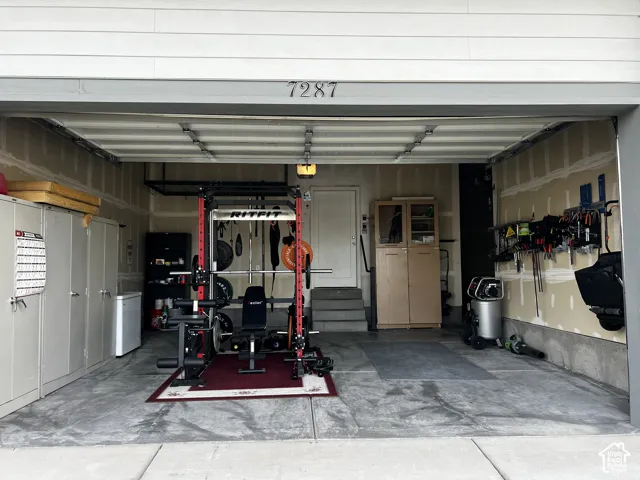 Attached two-car garage with a concrete floor, featuring built-in cabinetry and wall-mounted storage
