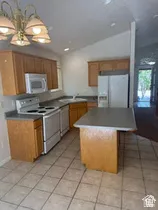 Vaulted ceiling kitchen featuring wood-finish cabinetry, tile flooring, and a center island