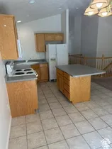 Kitchen featuring wood-finish cabinetry, tile flooring, and a central island with countertop space