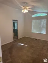 Vaulted ceiling with a ceiling fan light fixture, arched transom window, and carpet flooring