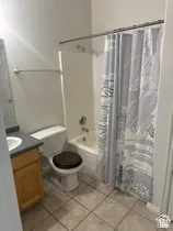 Full bathroom featuring a white tub, toilet, and a vanity with wood-finish cabinetry