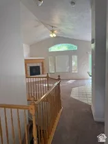 Vaulted ceiling with an arched transom window, wood-finish fireplace mantel, and two-tone flooring