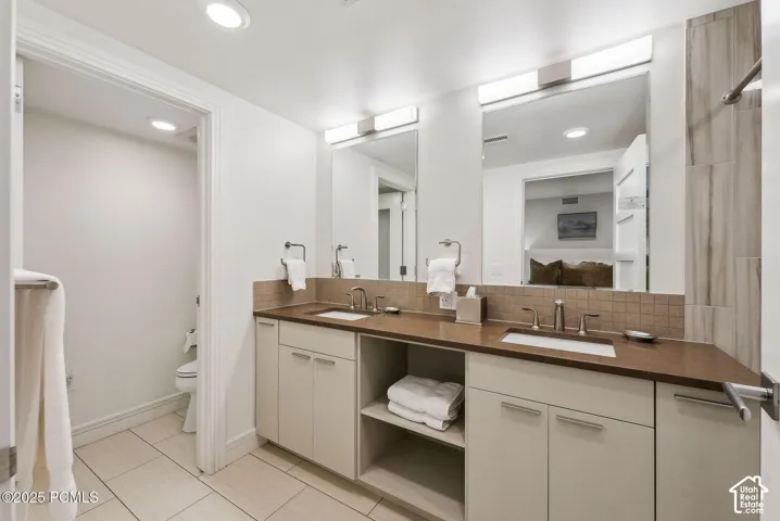 Dual vanity with integrated sinks, expansive counter space, square tile backsplash, and recessed lighting