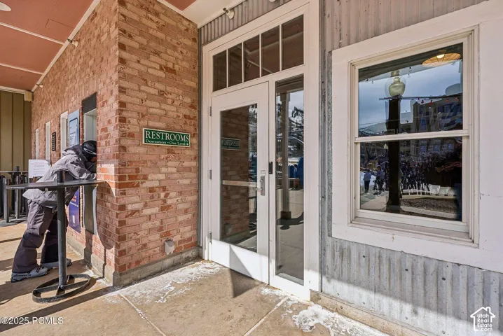 Brick and corrugated metal exterior with a white trim window and glass-panel double doors
