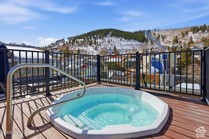 Rooftop deck featuring an octagon-shaped hot tub with a stainless steel handrail, composite decking, and metal railings