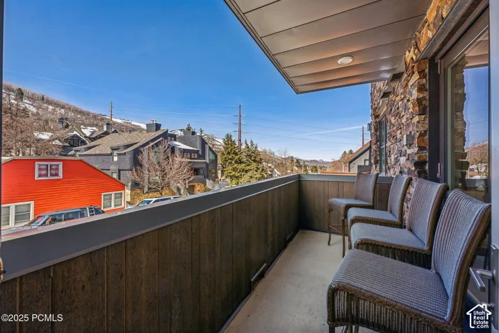 Covered balcony featuring stone exterior wall, wood-finish paneling, and concrete flooring