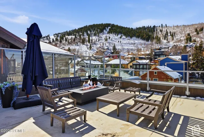Rooftop patio with a fire pit, concrete flooring, and glass panel railings