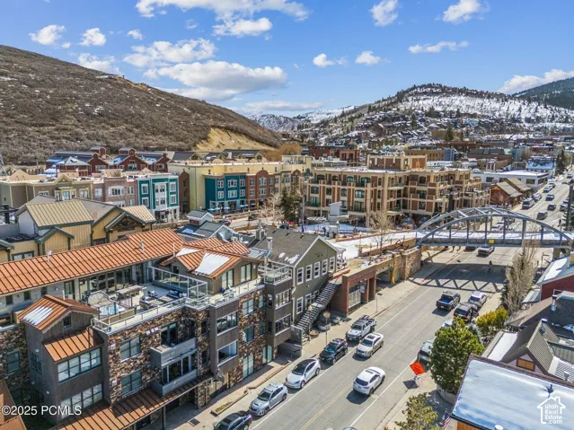 Urban landscape with diverse architectural styles, featuring multi-story buildings, pitched and flat roofs, and a prominent arched bridge over a thoroughfare
