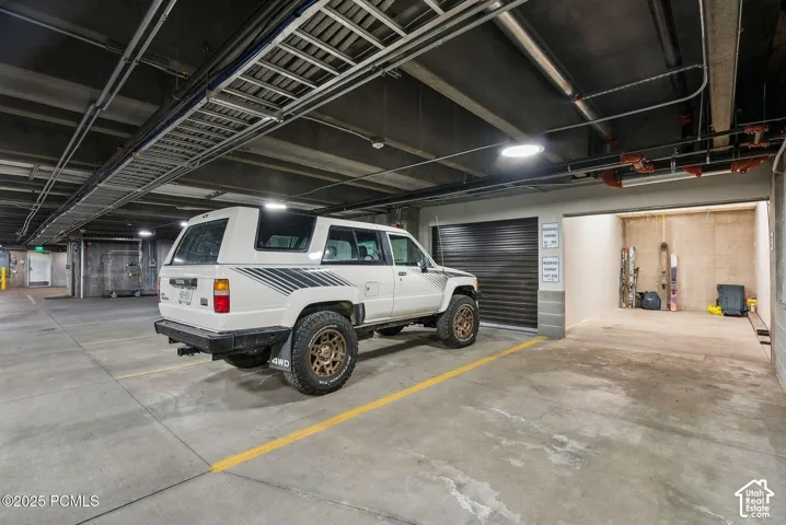 Private garage space with a black roll-up door, concrete flooring, and ample storage capacity