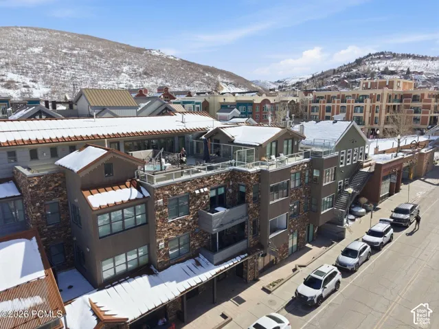 Multi-level building with stone and panel siding, featuring multiple balconies and rooftop deck spaces