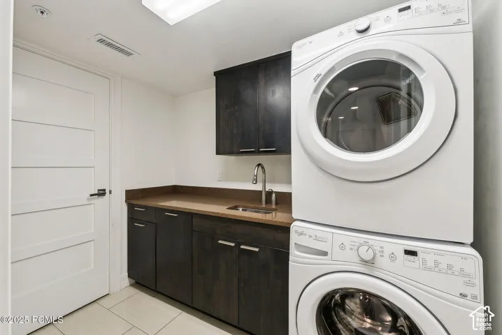 Built-in cabinetry with a sink and countertop, complemented by a stacked washer and dryer