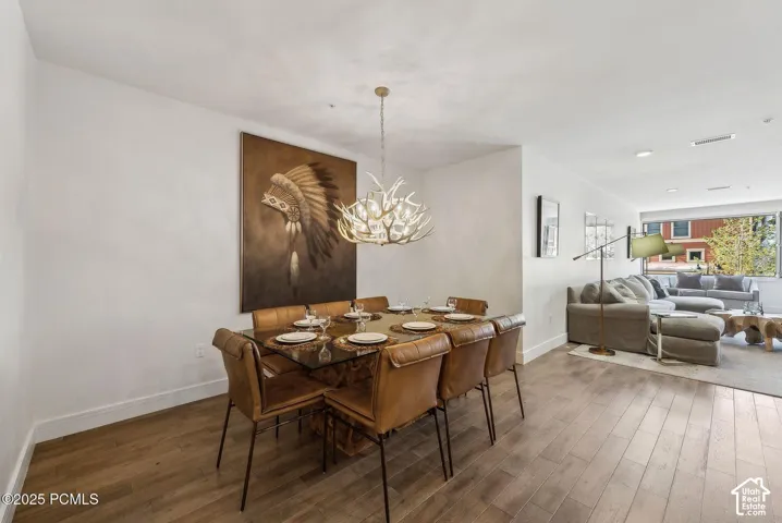 Open-concept living space with wood-finish flooring, recessed lighting, and a modern antler-design chandelier