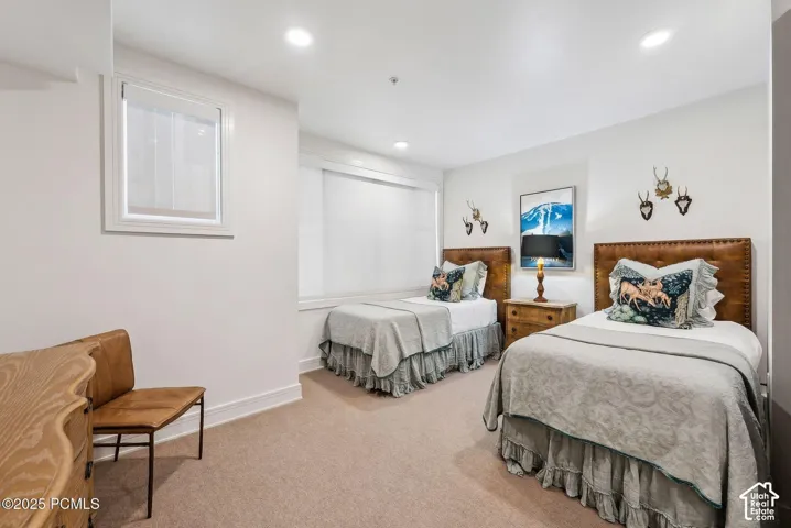Recessed ceiling lighting, window with roller shade, neutral carpeting, and white wall finishes