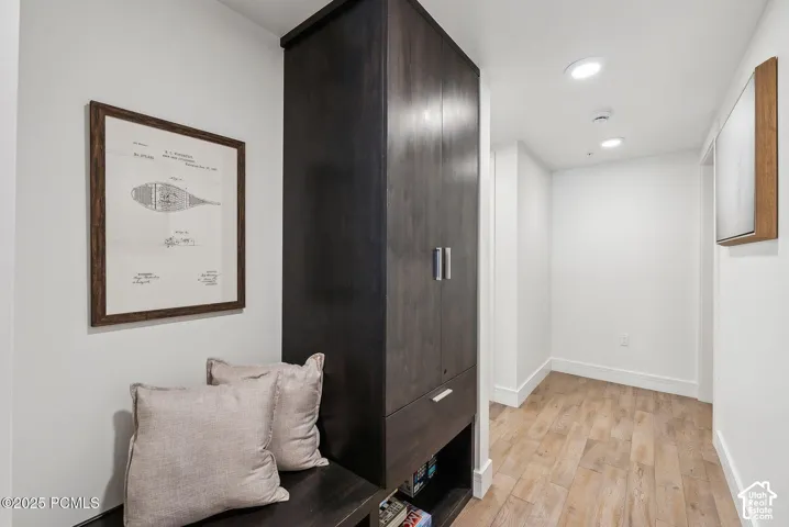 Built-in dark wood-finish cabinetry, integrated bench seating, wood-finish flooring, recessed ceiling lighting, and white wall finishes