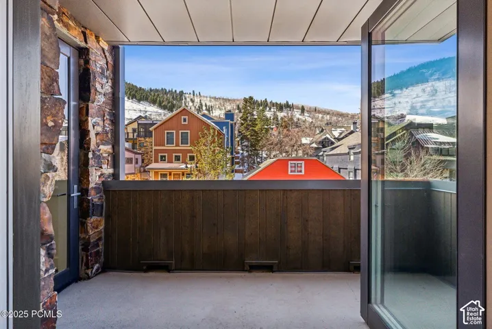Private balcony with stone column accents, wood-paneled railing, and concrete flooring