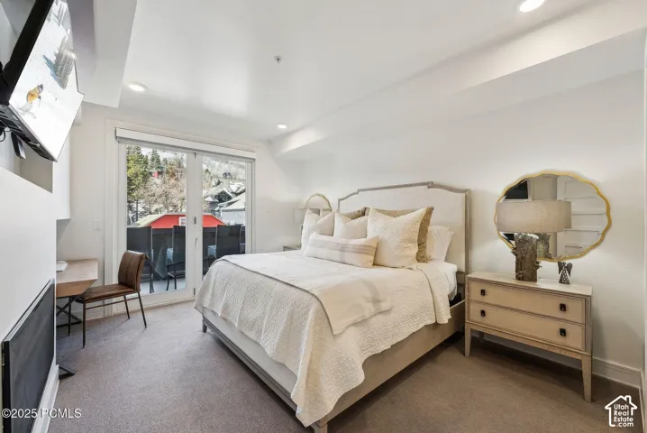 Recessed lighting, light-toned carpeting, a built-in desk, and a private balcony with sliding glass doors