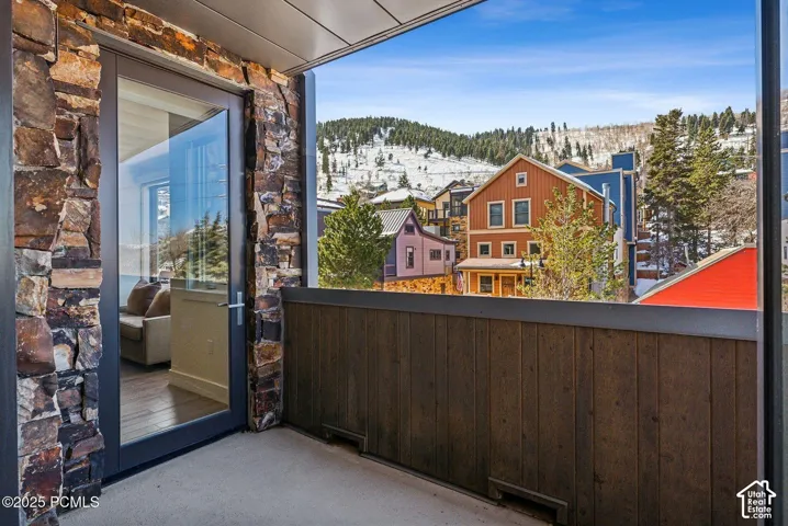 Private balcony with stone veneer accents, wood-finish paneling, and a full-light glass door