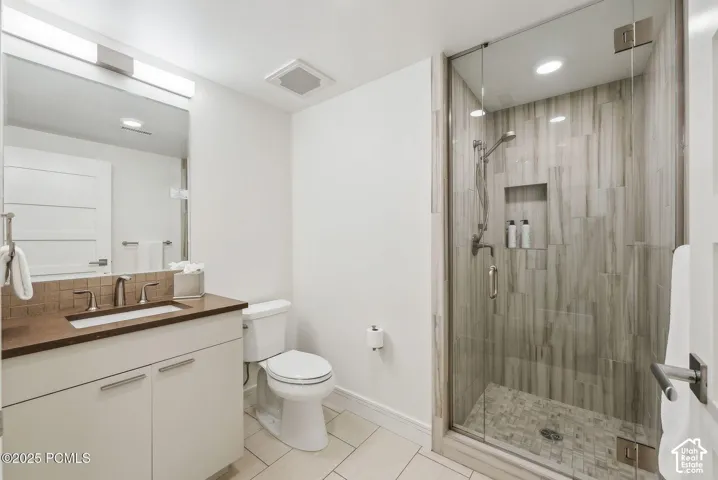 Glass-enclosed shower with a tiled surround, recessed niche, and mosaic floor