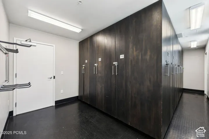 Wall-to-wall storage lockers with brushed metal hardware, durable flooring, recessed lighting, and a neutral wall palette