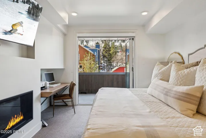 Built-in fireplace, recessed lighting, wood-finish built-in desk, built-in shelving, and balcony access